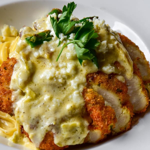Crispy breaded chicken cutlets topped with creamy sauce, crumbled cheese, and fresh parsley.